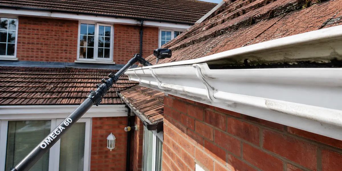 A professional high-reach wireless camera surveying a residential uPVC roof gutter during an inspection in West Wiltshire.
