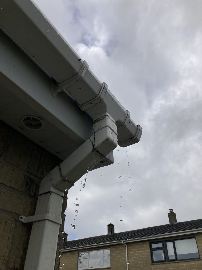 A leaking uPVC gutter running outlet union joint dripping water, illustrating the need for professional gutter repair services in West Wiltshire